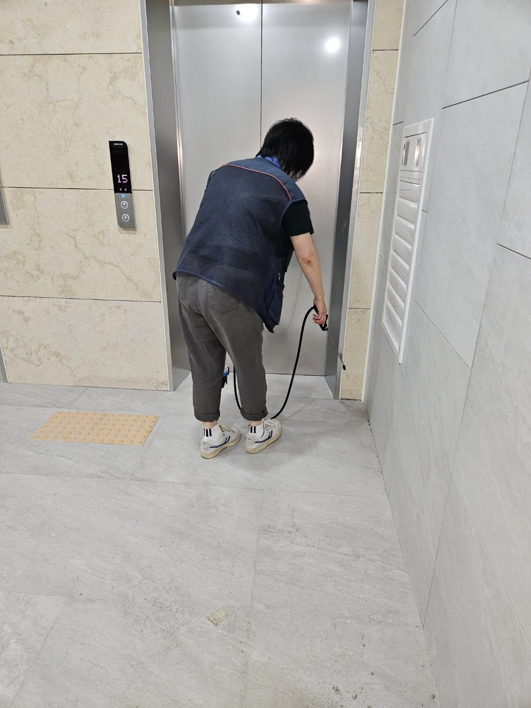 엘리베이터 홀 바닥과 벽면 경계를 방역하는 작업자